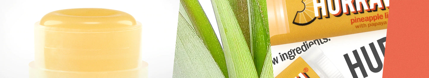 Lähikuva Hurraw! Ananas-huulivoidepuikosta, vihreitä lehtiä ja osittain näkyvä pakkaus tekstillä "HURR" kirkkaankeltaisella etiketillä; puolimatta sylinterinmuotoinen tuubi, kirkkaankeltainen tausta
