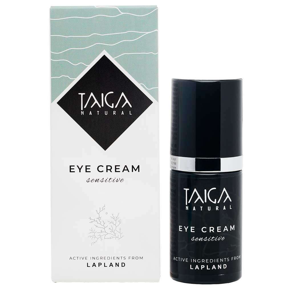 Taiga Cosmetics Silmänympärysvoide Herkälle Iholle; pullo Taiga Natural Eye Cream Sensitive -tuotetta pakkauksensa vieressä, minimalistinen suunnittelu korostaen Lapista peräisin olevia vaikuttavia ainesosia; sekä pullo että rasia valkoisia mustin groteskitekstein; rasia mattapintainen ja suorakulmainen; etiketissä brändi- ja tuotenimi; ei ihmisiä tai käsiä; vaalea, kevyt tausta, tavanomainen tuotekuva.