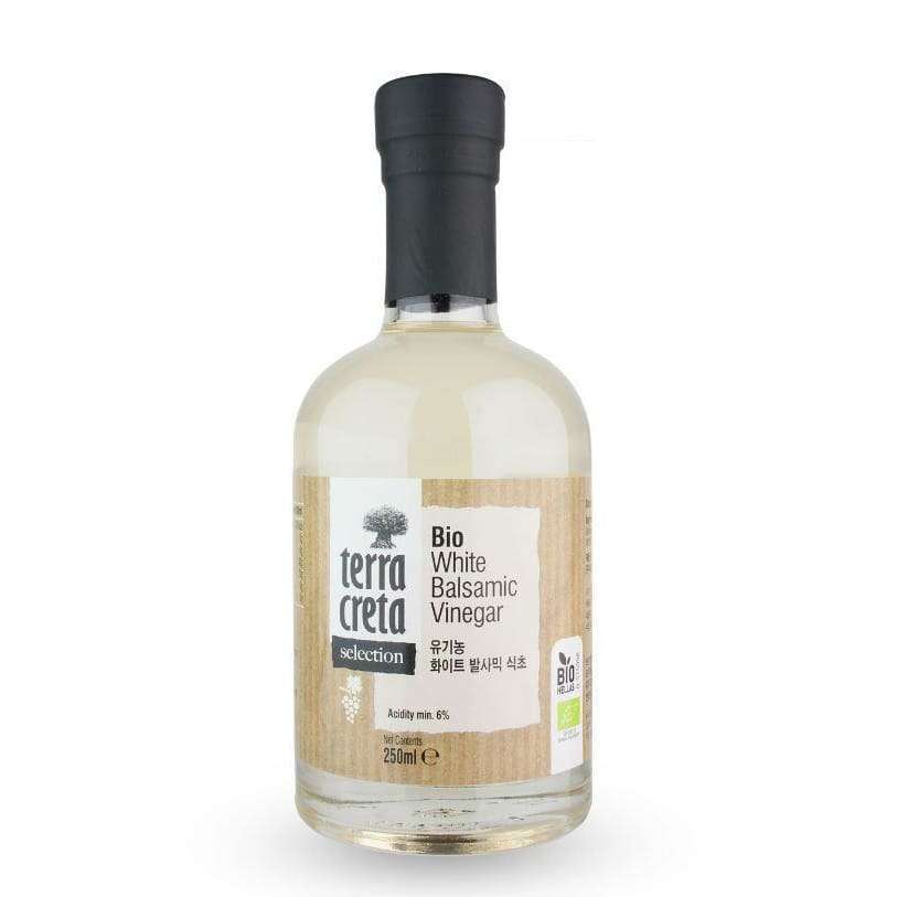 Terra Creta Luomu Balsamiviinietikka -pullo, 250 ml; kirkas, sylinterimäinen lasipullo mustalla kierrekorkilla, sisällä läpinäkyvää nestettä; mattapintaisessa beigessä paperietiketissä englannin- ja koreankielistä tekstiä sekä luomusertifiointimerkkejä; kuvattu pystyssä yksiväristä taustaa vasten, ei ihmisiä tai muita esineitä.