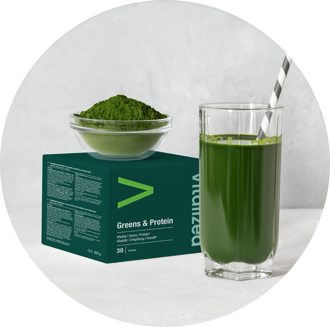 Vitalized Greens & Protein; lasillinen vihreää juomaa raidallisella pillillä, kulho vihreää jauhetta ja vihreä laatikko tekstillä Greens & Protein aseteltuna valkoiselle pinnalle; juoma kirkkaassa lieriömäisessä lasissa; pillissä vuorottelevat valkoiset ja vaaleanvihreät viistoraidat; kulho pyöreä, keraaminen tai posliininen mattapinnalla; laatikko suorakaiteen muotoinen, mattapintainen, kirkkaanvihreä, lihavoitua valkoista groteskitekstiä; ei ihmisiä kuvassa.