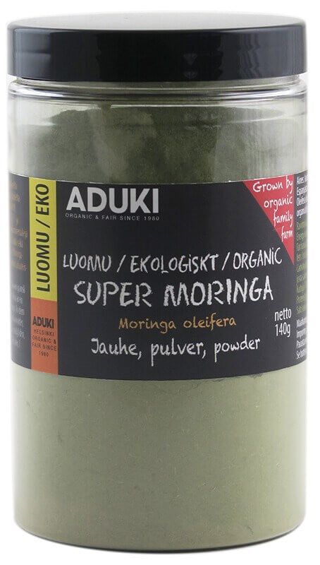 Aduki Luomu Moringajauhe, 140 g, kirkkaassa muovipurkissa; purkki sylinterimäinen ja täynnä hienoa vihreää jauhetta; musta-keltaisessa etiketissä lohkokirjaimia, monikielistä tekstiä sekä punainen huomiomerkintä luomutilan kasvatuksesta; etiketti keskitetty purkin rungolle; tausta valkoinen ja tasaisesti valaistu.