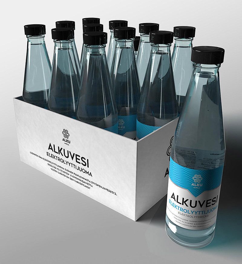 A box containing twelve clear glass bottles labeled Alkuvesi Elektrolyyttijuoma, each with black plastic screw caps. The bottles are cylindrical and have matte blue-and-white labels with sans-serif text, positioned toward the viewer for legibility. All items rest in an open cardboard tray on a smooth, pale background under neutral lighting.