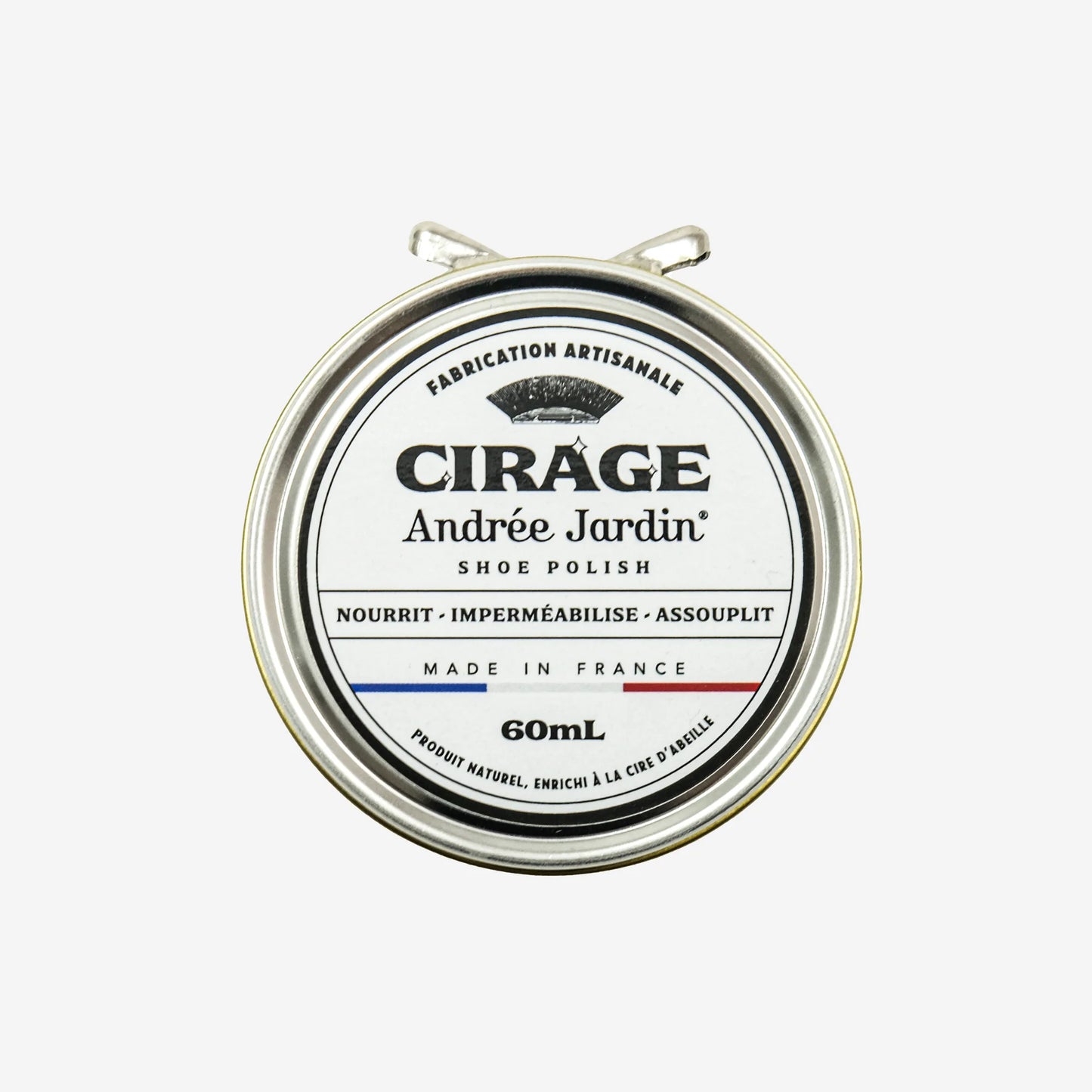 Andree Jardin Kenkienkiillotusvaha, Väritön; pyöreä Andrée Jardin -kenkävahatölkki, kannessa teksti "Cirage" ja tilavuus 60 mL; kansi mattapintaista hopeanväristä metallia, pyöreä paperietiketti hillityin sävyin; antiikva- ja groteskikirjasinta yhdistelevä teksti kertoo tuotteen ravitsevista, vedenpitävistä ja pehmentävistä ominaisuuksista, valmistettu Ranskassa; valkoinen tausta ilman ihmisiä tai rekvisiittaa.