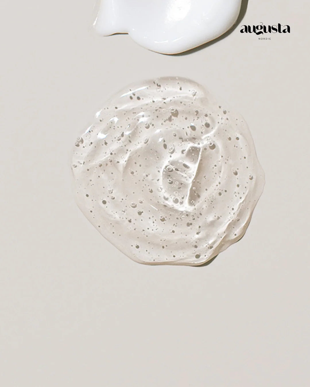 Augusta Nordic Soothing Hydration Gel; kirkkaan geelin ja valkoisen voiteen läiskiä lepää vaalealla beigellä pinnalla, oikeassa yläkulmassa musta augusta NORDIC -logo; kirkkaassa geelissä lukuisia pieniä kuplia ja heijastava, kiiltävä pinta; valkoinen voide läpikuultamaton ja kermainen tekstuuriltaan; molemmat tuotteet esitettynä ilman pakkausta tai astiaa; kuvausympäristö pelkistetty, ei ihmisiä tai rekvisiittaa näkyvissä.