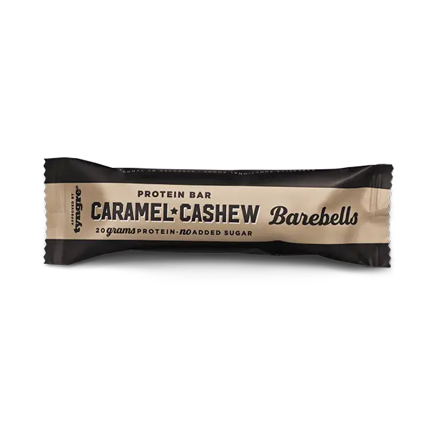 Barebells Caramel-Cashew Proteiinipatukka; Barebells Caramel Cashew -proteiinipatukka beigessä ja mustassa pakkauksessa, mattapinnalla ja suorakulmaisella muodolla; kääreessä lihavaa groteskitekstiä ”20 grams protein” ja ”no added sugar”; ei ihmisiä tai käsiä näkyvissä; tausta neutraali ja vaalea; Barebells Caramel Cashew -proteiinipatukka beigessä ja mustassa pakkauksessa, merkitty 20 grammalla proteiinia ilman lisättyä sokeria, tarjoaa maukkaan ja kätevän tavan tukea aktiivista elämäntapaa.