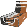 Barebells Cookies-Caramel Proteiinipatukka; laatikko Barebells-proteiinipatukoita, maku cookies & caramel; pakkaus on suorakulmainen mattamustalla pohjalla, ruskein yksityiskohdin ja valkoisin lisäelementein; patukat on aseteltu riveihin avonaisen laatikon sisällä; laatikossa isokokoista groteskitekstiä ”20 grams of protein” ja ”no added sugar”; ei ihmisiä tai käsiä näkyvissä; tausta on yksivärinen ja pinnaltaan tasainen.