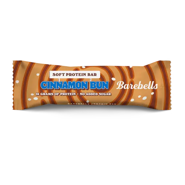 Barebells Soft Cinnamon Bun Proteiinipatukka; Barebells Cinnamon Bun -pehmeä proteiinipatukka ruskeassa kääreessä kanelipyörrekuvituksin; kääre matta ja näyttää tuotenimen, 16 grammaa proteiinia ja ei lisättyä sokeria lihavoidulla groteskikirjasimella; avaamaton patukka keskitettynä valkoiselle taustalle, ei ihmisiä tai muita esineitä.