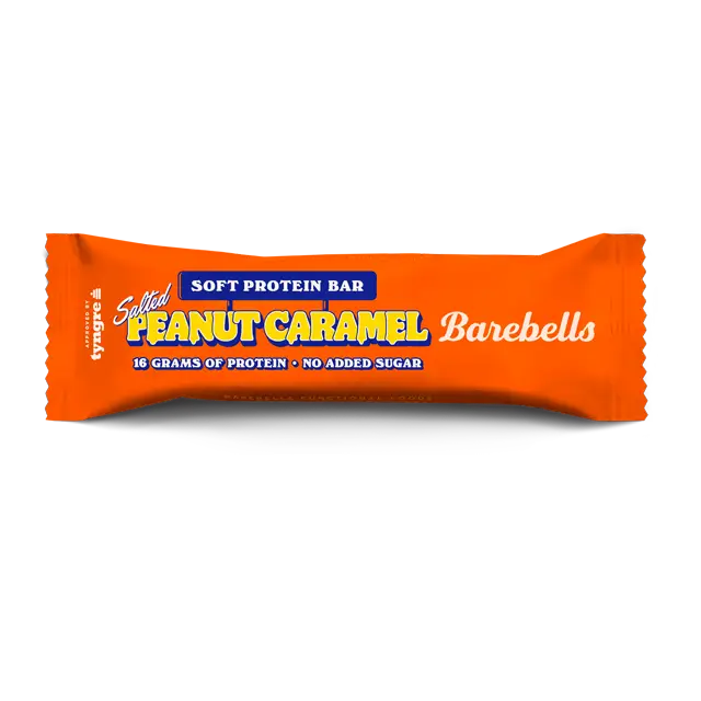 Barebells Soft Salted Peanut Caramel Proteiinipatukka; oranssikääreinen Barebells-pehmeä proteiinipatukka mattapinnalla, suorakaiteen muotoinen saumatuin päin; pakkaus kertoo maun olevan suolainen maapähkinäkaramelli sekä 16 grammaa proteiinia ja ei lisättyä sokeria lihavoiduin groteskikirjaimin; ei ihmisiä tai käsiä; vaalea tausta; tuote sopii virkistäväksi proteiinilisäksi.