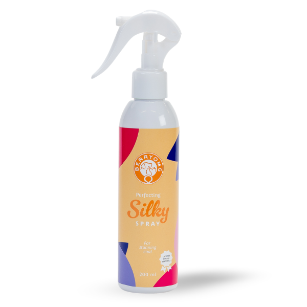 Berry OMG Perfecting Silky Spray; valkoinen suorakulmainen muovinen suihkepullo mattapinnalla, pystyssä; musta liipaisinsuutin; etiketissä teksti Perfecting Silky Spray ja värikkäitä geometrisia grafiikoita; painettu teksti kertoo 200 ml tilavuudesta ja käytöstä turkkien selvittämiseen; ei ihmisiä tai käsiä; vaalea tausta, tuote keskellä kuvaa.