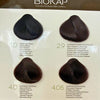 Biokap Nutricolor Delicato Kestoväri; neljä hiusvärinäytettä merkinnöin: 1.0 Natural Black, 2.9 Dark Chestnut Chocolate, 4.0 Natural Chestnut ja 4.05 Chocolate Chestnut näytetään Biokap-hiusvärikartassa vaakarivissä; jokainen näyte kiinnitetty suorakulmaiseen valkoiseen korttiin painetuin mustin etiketein ja brändinimellä groteskikirjasimella; ei ihmisiä tai käsiä kuvassa, tausta valkoinen.