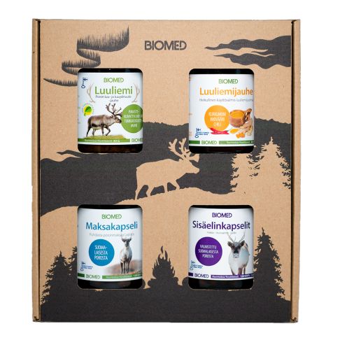 A cardboard box with four Biomed supplement jars is displayed; the jars have matte, cylindrical plastic bodies and white caps. Each jar shows a distinct label color, readable brand name “Biomed,” and various animal illustrations. The setting is a printed background with silhouettes of trees and reindeer in neutral tones. No people or hands are present in the shot.