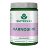 Bioteekki Karnosiini; vihreä-valkoinen purkki tekstillä "BIOTEEKKI KARNOSIINI" violetilla nauhalla, sisältää 60 kapselia; muovipurkki mattapinnalla, lieriön muotoinen kierrekorkillinen; etiketti lihavoitua sans-serif-tekstiä lohkokirjaimin eri fonttipainoin; pääteksti sisältää "AMINOHAPPO", "PITKÄVAIKUTTEINEN" ja "HELPPOSTI NIELTÄVÄ" aminohappokaavasta; kuvattu valkoista taustaa vasten, ei ihmisiä tai toimintaa näkyvissä.