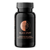 A black plastic supplement bottle with a matte finish and cylindrical shape. The label reads “Black Stuff Microbiome Wellbeing Fulvic Acid Rich Supplement.” A circular logo displays a stylized tree with branching lines. Typography is sans-serif, printed in white on a dark label. The bottle stands upright on an unadorned surface. No people or hands are visible in the image.