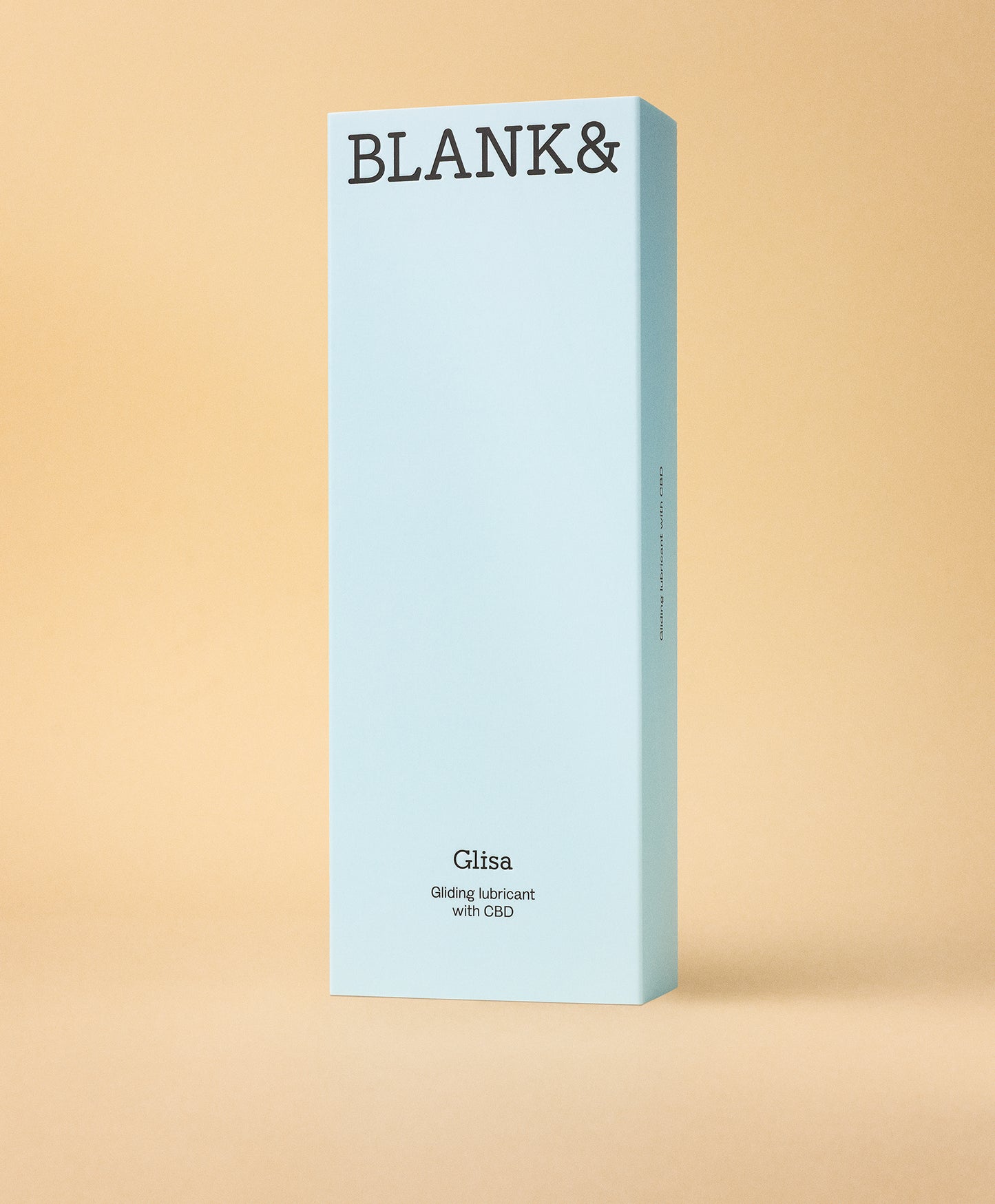 Blank& Glisa Liukuvoide; vaaleansininen suorakulmainen rasia tekstillä BLANK& ja Glisa Gliding lubricant with CBD seisoo pystyssä beigeä taustaa vasten; rasia matta, pahvia, siistein reunoin; yksinkertaista tummaa groteskikirjasinta etiketissä; ei ihmisiä tai muita esineitä kuvassa; kuva suoraan edestä silmän korkeudelta tasaista taustaa vasten.