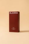 Blank& Veya Kasvosuihke; tummanpunainen suorakulmainen rasia tekstillä BLANK& yläosassa, alla teksti Veya Glass Glow Face Mist with CBD ja maininta säteilevästä lopputuloksesta, vaaleaa beigeä taustaa vasten; rasian pinta sileä ja kulmat terävät; teksti selkeällä nykyaikaisella groteskikirjasimella; ei ihmisiä tai käsiä, kuva otettu edestä tasaisessa valaistuksessa.