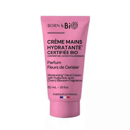 Born to Bio Hyaluronic Acid Hand Cream: pinkki tuubi Born to Bio -kosteuttavaa käsivoidetta kirsikankukkatuoksulla, 50 ml, merkitty ranskaksi ja englanniksi; muovituubi on mattapintainen ja pyöristetyin kulmin; teksti käyttää lihavoitua groteskikirjasinta brändinimelle ja pienempää tavallista fonttia muulle tiedolle; ei ihmisiä tai käsiä näkyvissä, tuote kuvattu keskitetysti valkoista taustaa vasten.