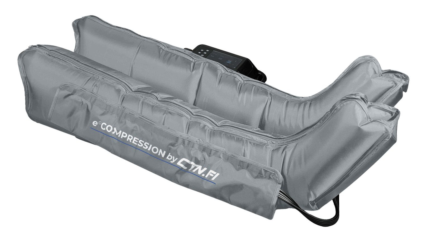 CTN e°COMPRESSION Kompressiolahkeet: harmaat kompressiolahkeet sileästä mattamateriaalista, liitetty joustaviin letkuihin ja suorakulmaiseen ohjausyksikköön; setti lepää tekstuurittomalla vaalealla alustalla; yhdessä lahkeessa selkeä groteskiteksti "eCOMPRESSION by GymFi"; pakkausta tai ihmisiä ei näy; kuva on otettu ylhäältä.