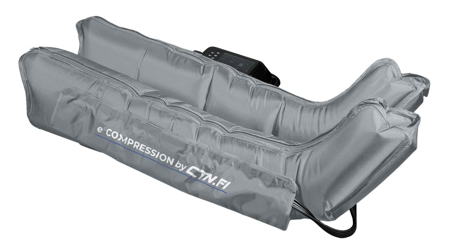 CTN e°COMPRESSION Kompressiolahkeet: harmaat kompressiolahkeet sileästä mattamateriaalista, liitetty joustaviin letkuihin ja suorakulmaiseen ohjausyksikköön; setti lepää tekstuurittomalla vaalealla alustalla; yhdessä lahkeessa selkeä groteskiteksti "eCOMPRESSION by GymFi"; pakkausta tai ihmisiä ei näy; kuva on otettu ylhäältä.