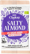Chokay Luomu Tumma Suolainen Manteli Suklaa; Chokay Salty Almond -tumma suklaapatukka, 0 % lisättyä sokeria; violetti-valkoinen pakkaus kaakaopalkokuvituksin; kääre suorakaiteen muotoinen mattapinnalla; pääteksti lihavoituna groteskina, lisätiedot pienemmällä painatuksella; tuote tasaisella alustalla; ei ihmisiä tai käsiä kuvassa.