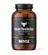 DENSE Härän Kivekset; ruskea muovipullo sylinterinmuotoisena mustalla mattapintaisella etiketillä; etiketissä teksti "Beef Testicles with Oysters and Liver, Grass-Fed, 240 Capsules, 400 mg"; keskellä lihavoitu härän pää -kuvitus; pääosin valkoista groteskitekstiä; pullon korkki on yhtenäisen musta rihlatuin reunoin; tausta valkoinen, tuote keskitettynä kuvassa.