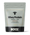 DENSE Heraproteiini Suklaa; hopeanvärinen ja musta mattapintainen pystypussi, suorakulmainen muodoltaan, esittää selkeää painettua tekstiä Whey Protein Grass-Fed ja sanan DENSE lihavan lehmäääriviivan alla; etuetiketissä yksinkertaista lohkotypografiaa, korostaen suklaan makua, luonnollisia makuja, korkeaa biosaatavuutta ja laiduntavista lähteistä peräisin olevia ainesosia; tuote esillä yksivärista taustaa vasten studiotyylisessä kuvassa.