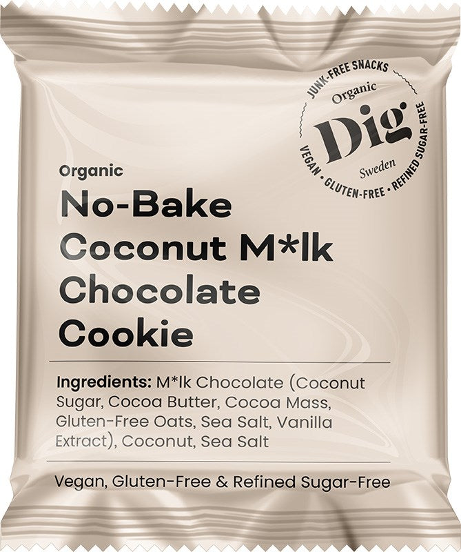 Dig Luomu Kookossuklaakeksi; beige, mattapintainen suorakulmainen pussi, merkitty ”Dig Organic No-Bake Coconut M*lk Chocolate Cookie”; etupuolella lihavaa groteski- ja kaunokirjoitusfonttia, jossa vegaani-, gluteenitonta ja puhdistetusta sokerista vapaata koostumusta koskevat väitteet ja luomu-ainesosaluettelo; ei ihmisiä tai käsiä näkyvissä; tausta vaalea, koko pussi näkyvissä kuvassa.