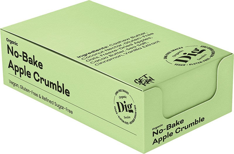 Dig Luomu Omenacrumble; vihreä pahvilaatikko mattapinnalla suorakulmion muotoisena; etupinnassa lihavaa, suuraakkosista groteskitekstiä ”Organic No-Bake Apple Crumble” ja avainainesosat pienemmällä tekstillä; cashewvoi, kaakaovoi ja omenat sisältyvät ainesosiin; muita ominaisuuksia kuten vegaanisuus ja gluteenittomuus näkyy etiketissä; tausta yksivärinen; ei ihmisiä näkyvissä; vihreä laatikko, merkitty Organic No-Bake Apple Crumble, listaa ainesosia kuten cashewvoi, kaakaovoi, omenat ja muita.