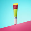 Djusie Cucumber Slice Awakening Eye Cream; tuubi pystyssä pinkillä alustalla sinistä taustaa vasten, vihreä pakkaus keltaisella korkilla ja valkoisella pohjaosalla; etiketissä selkeästi näkyvä tuotenimi groteskifontilla; tuubin pinta vaikuttaa mattapintaiselta; kuvassa ei ihmisiä tai toimintaa.