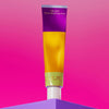 Djusie The Juice Moisturizing Power Fluid; värikäs tuubi pystyssä kiiltävällä yhtenäisen violetilla pinnalla; tuubi yksinkertaisen sylinterimäinen, etiketissä selkeää ja lihavoitua kirjasinta; taustalla kirkkaan vaaleanpunainen liukuväri ylhäältä alas; ei ihmisiä eikä käsiä näkyvissä.