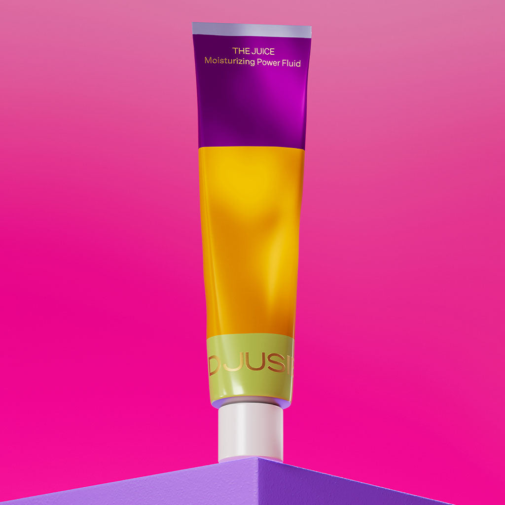Djusie The Juice Moisturizing Power Fluid; värikäs tuubi pystyssä kiiltävällä yhtenäisen violetilla pinnalla; tuubi yksinkertaisen sylinterimäinen, etiketissä selkeää ja lihavoitua kirjasinta; taustalla kirkkaan vaaleanpunainen liukuväri ylhäältä alas; ei ihmisiä eikä käsiä näkyvissä.