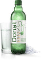A green glass bottle labeled “Donat” is shown upright on a flat surface, next to a cylindrical clear glass containing sparkling mineral water with visible bubbles. Small white mineral crystals are scattered nearby. The bottle has a glossy finish and the label features clear, bold sans-serif text. The scene is evenly lit with no people or hands present. A green bottle labeled Donat stands next to a glass filled with sparkling mineral water and some white mineral crystals on the surface.