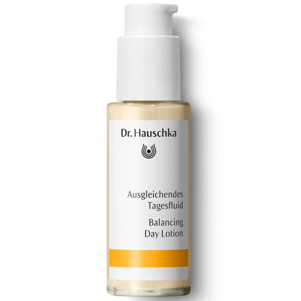 Dr. Hauschka Tasapainottava Kosteusvoide; pullo Dr. Hauschka Balancing Day Lotion -tuotetta käytännöllisellä pumppuannostelijalla; astia lieriömäinen, vaikuttaa kirkkaasta lasista mattavalkoisella etiketillä ympärillään; etiketissä mustia ja oransseja tehosteita, yksinkertaista tikkukirjasinta, teksti sekä saksaksi että englanniksi; tausta tasaisesti valaistu, neutraali valkoinen; ei ihmisiä tai käsiä näkyvissä.