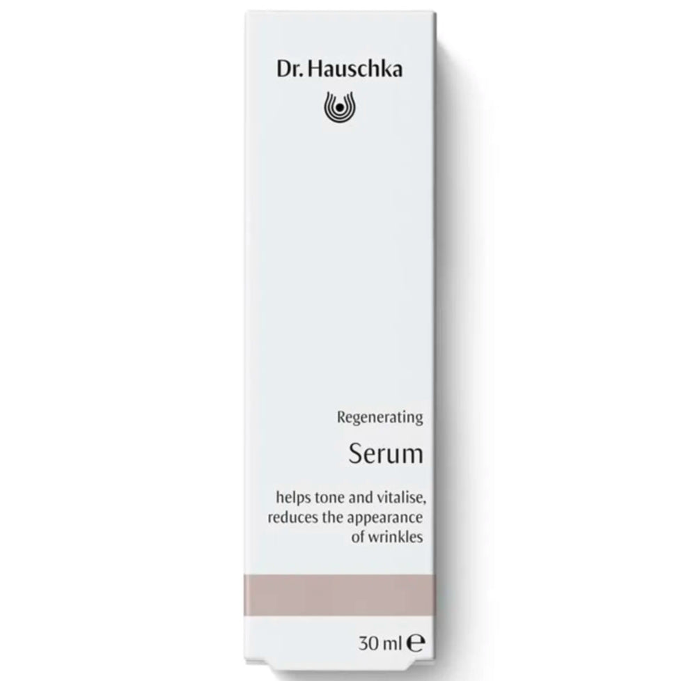 White box of Dr. Hauschka Regenerating Serum, 30 ml. Rectangular, upright carton with a matte finish. Main colors are white, black, and beige; typography is clean and sans-serif for product info. Visible printed text includes: helps tone and vitalise, reduces the appearance of wrinkles and supports a youthful complexion. The background is plain; no people or extra elements shown. The packaging is minimal with elegant black and beige accents.
