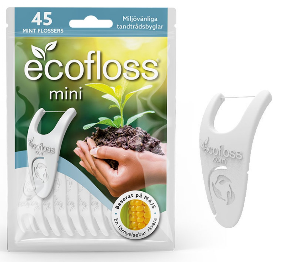 Ecofloss Mini Hammaslankain; pakkaus ecofloss mini -minttuhammaslankaimia, kuvassa kädet pitelemässä maata ja tainta; yksi valkoinen, kaareutuvapäinen hammaslankain on esillä mattapintaisen suorakulmaisen pakkauksen ulkopuolella; etiketissä selkeää groteskitypografiaa vihreällä ja mustalla; tausta valkoinen; teksti korostaa tuotteen ympäristöystävällisyyttä ja valmistusta uusiutuvasta maissista.