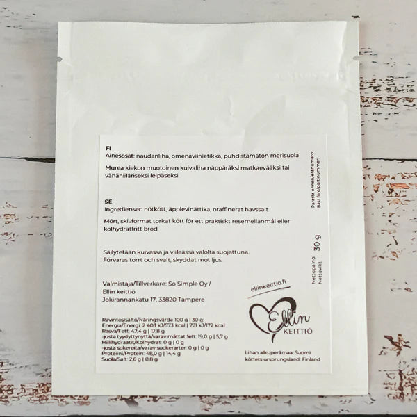 Ellin Lihakiekko Maustamaton; valkoinen elintarvikepussi suomenkielisin tekstein, ainesosatiedoin, ravintotiedoin ja Ellin Keittiö -logolla; pussi suorakaiteen muotoinen mattapinnalla ja painetulla etiketillä lihavoidulla tikkukirjasimella; aseteltuna vaalealle puupinnalle; ei ihmisiä tai käsiä näkyvissä; pussi korostaa laadukkaita ainesosia suomenkielisillä merkinnöillä vaalealla puupinnalla.