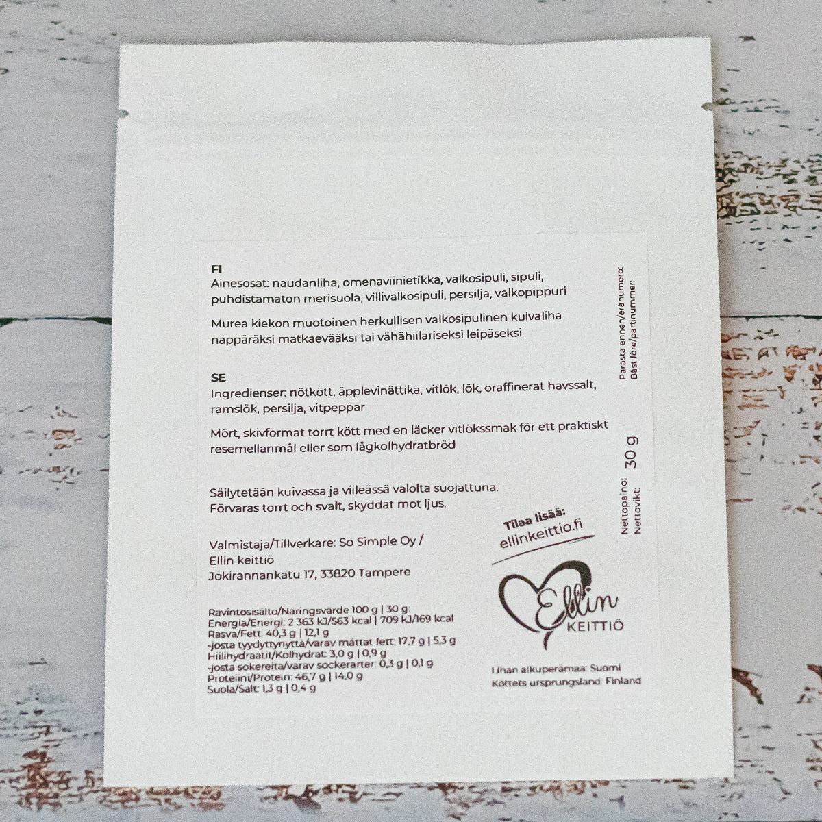 Ellin Lihakiekko Valkosipulinen; valkoinen elintarvikepakkaus suomenkielisin tekstein, jotka listaavat ainesosat, valmistusohjeet, säilytysohjeet ja yrityksen yhteystiedot; Ellin Keittiö -brändi kokinhattulogolla oikeassa alakulmassa; suorakaiteen muotoinen mattapinta selkeällä mustalla painetulla tekstillä eri fonttipainoissa, suurin osa tiedoista vasemmalle tasattuna; ei ihmisiä tai käsiä näkyvissä, tuote kuvattu tasaisella taustalla.