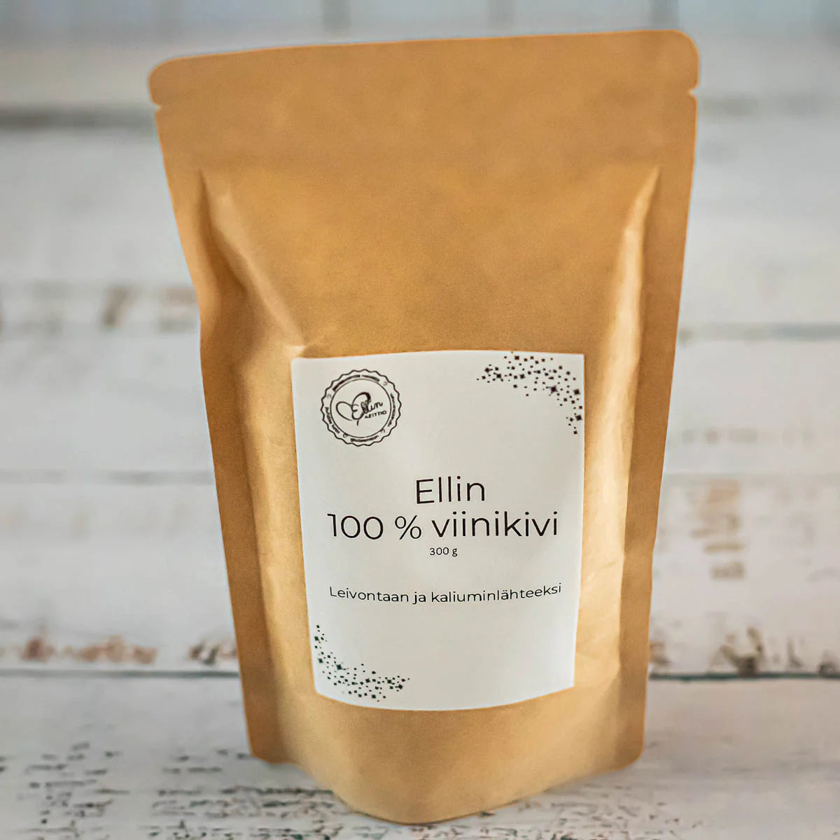 Ellin 100 % Viinikivi; ruskea uudelleensuljettava pussi, jossa lukee Ellin 100% viinikivi, 300g, seisoo vaalealla puupinnalla; mattapintainen pussi on suorakulmainen ja pystyssä; etiketti on valkoinen mustalla ja oranssilla groteskitekstillä, mukana teksti "Leivontaan ja kaliuminlähteeksi"; kuvassa ei näy ihmisiä tai muita esineitä.