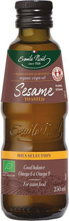 Emile Noel Luomu Paahdettu Seesamiöljy, ruskea lasipullo kiiltäväpintainen, sylinterimäinen ja kapea kaula; etiketissä vihreä-kultainen Emile Noel -brändäys, teksti "organic virgin oil", tilavuus 250 ml sekä maininta Omega 6 ja 9 rasvahapoista sekä sopivuudesta aasialaiseen ruokaan; ei ihmisiä eikä käsiä näkyvissä, tausta pelkistetty, kuva suoraan edestä silmän korkeudelta.