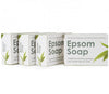 Epsom Suolasaippua; neljä Epsom Soap -saippuapakkausta vihrein lehtikuvioin rivissä; pakkaus suorakaiteen muotoinen mattapinnalla, pääosin valkoinen ja vihreä väritys; etuosassa etiketti groteskifontilla: Epsom Soap, traditional bathing remedy with added magnesium-rich Epsom Salts; ei ihmisiä tai käsiä; vaalea tausta, tavanomainen tuotekuvakulma.