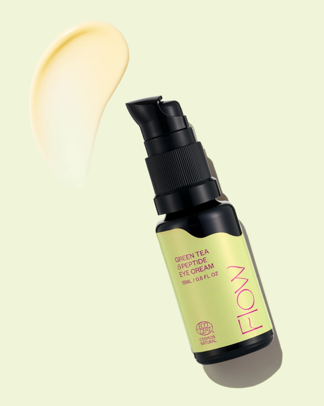 Pullo, jossa lukee Green Tea Peptide Eye Cream Flow-brändäyksellä, on aseteltu kulmittain vaalealle taustalle, vieressä peptideillä rikastettu kermainen sivelynäyte. Pullo on lieriömäinen, valkoinen puolikiiltävällä pinnalla ja tummanvihreää modernia pääteviivatonta tekstiä. Etikettiteksti on niukkaa ja selkeää. Ihmisiä tai käsiä ei näy. Kuva on lähikuva tuotevalokuvauksesta.