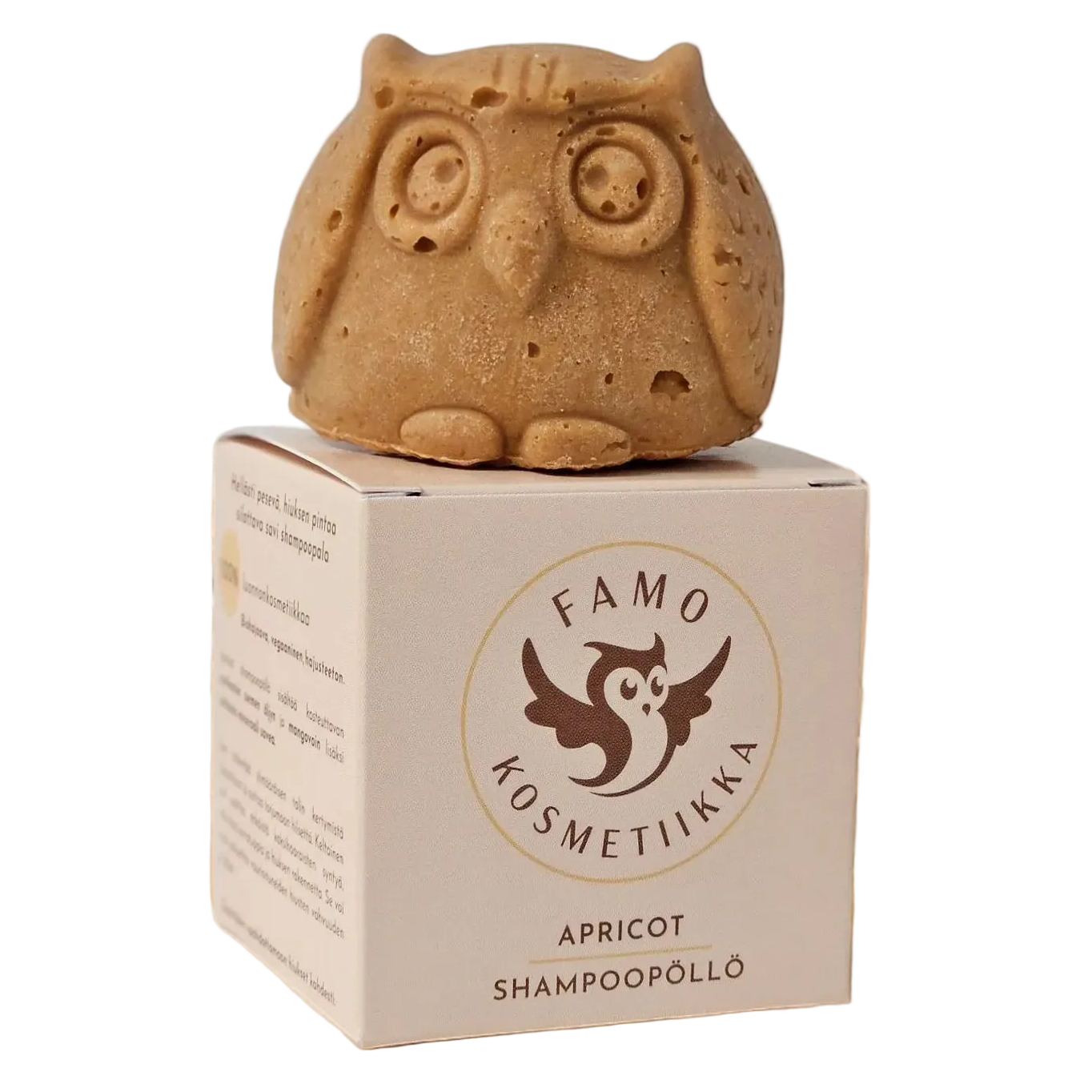 Famo Apricot Shampoopöllö: ruskea, mattapintainen pöllönmuotoinen kiinteä shampoopalanen suorakulmaisen rasian päällä; rasiassa teksti "Famo Kosmetiikka Apricot Shampoopöllö" selkeällä groteskikirjasimella sekä kuvitettu pöllölogo etuosassa; ei ihmisiä tai käsiä näkyvissä, tausta on yksinkertainen ja neutraali, lähikuva tuotteesta.