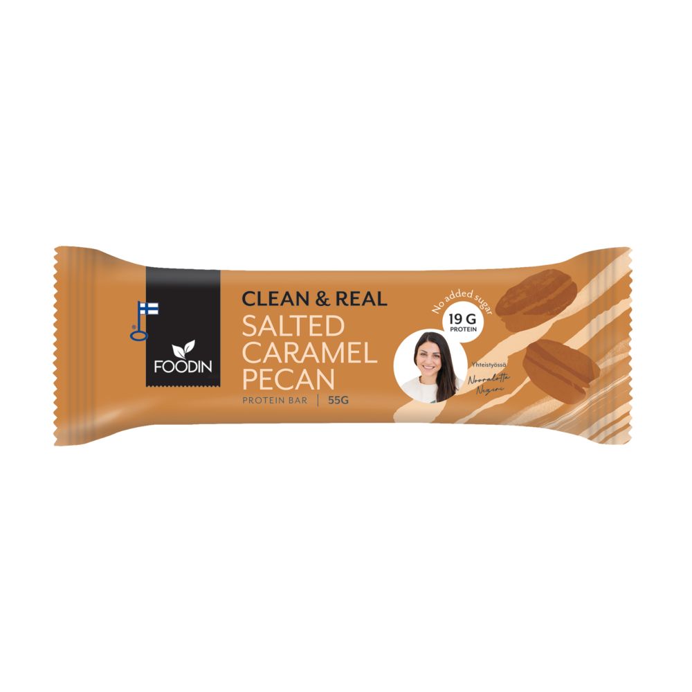 A Foodin Clean & Real Salted Caramel Pecan protein bar in orange matte packaging, rectangular shape, features images of pecans and a circular label stating 19g protein. Notable sans serif white and brown text. Small color photo of a smiling woman on the front. Product rests on a plain white background in a flat lay shot.