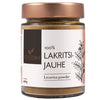 A glass jar labeled Foodin 100% Lakritsijauhe Licorice powder with a copper-colored metallic screw-on lid, clear cylindrical body, and matte finish label featuring stylized floral graphics. Packaging indicates 40g. Background is plain and uncluttered. Shot is product-focused without people or hands present.