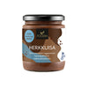 A jar of Foodin Herkkuisa, a delicious sugar-free vegan hazelnut chocolate spread featuring Finnish text and a black lid, is pictured against a white background. The cylindrical jar is clear glass or plastic with a matte paper label, displaying simple sans-serif and handwritten-style fonts. Label includes “HERKKUISA” in bold uppercase. The product sits upright on an even surface; no people or props are visible.
