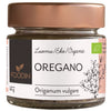 Foodin Luomu Oregano; pieni lasipurkki, metallinen kuparinvärinen kierrekansi, lieriömäinen läpinäkyvä runko; mattapintainen valkoinen etiketti kiertää purkkia, esittää brändin "Foodin", tuotenimen ja vihreitä yrttikuvituksia; yksinkertaista groteskitekstiä; vaalea tausta, ei toimintaa tai ihmisiä kuvassa.