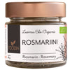 Foodin Luomu Rosmariini, lasipurkki ruusukultaisella metallikannella, sylinterin muotoinen ja läpinäkyvä, sisällä näkyy kuivattua rosmariinia; purkin pinta kiiltävä; etiketti tumma ja mattapintainen, valkoista groteskitekstiä suomeksi, saksaksi ja englanniksi, tuotenimi ja paino (18 g) sekä yksinkertaisia vihreitä kasvikuvituksia; tausta studiomainen valkoinen, ei ihmisiä eikä käsiä.