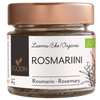 Foodin Luomu Rosmariini, lasipurkki ruusukultaisella metallikannella, sylinterin muotoinen ja läpinäkyvä, sisällä näkyy kuivattua rosmariinia; purkin pinta kiiltävä; etiketti tumma ja mattapintainen, valkoista groteskitekstiä suomeksi, saksaksi ja englanniksi, tuotenimi ja paino (18 g) sekä yksinkertaisia vihreitä kasvikuvituksia; tausta studiomainen valkoinen, ei ihmisiä eikä käsiä.