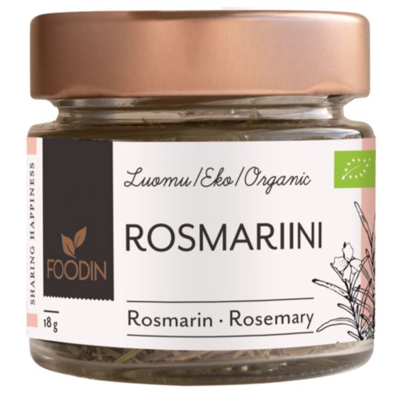 Foodin Luomu Rosmariini, lasipurkki ruusukultaisella metallikannella, sylinterin muotoinen ja läpinäkyvä, sisällä näkyy kuivattua rosmariinia; purkin pinta kiiltävä; etiketti tumma ja mattapintainen, valkoista groteskitekstiä suomeksi, saksaksi ja englanniksi, tuotenimi ja paino (18 g) sekä yksinkertaisia vihreitä kasvikuvituksia; tausta studiomainen valkoinen, ei ihmisiä eikä käsiä.