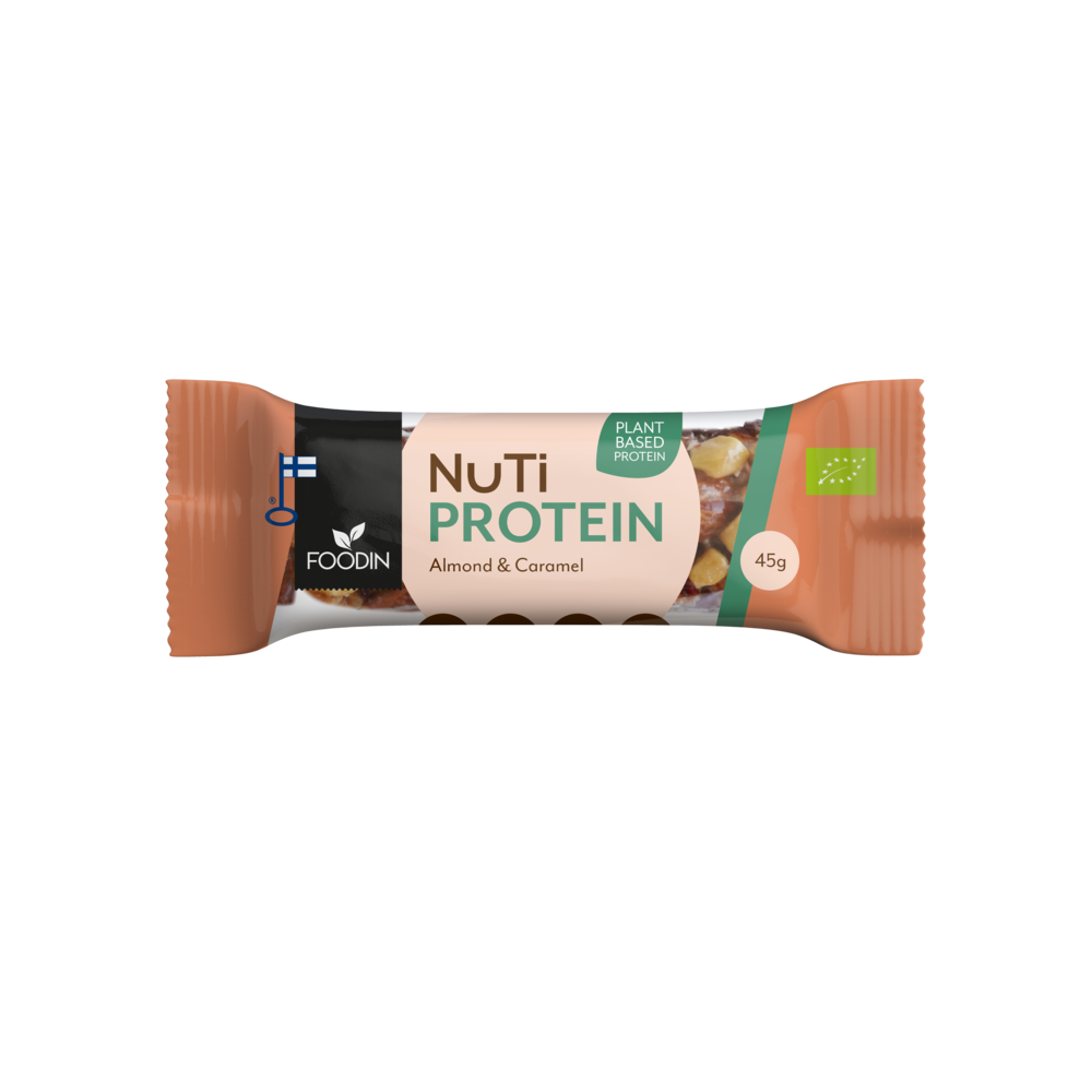 Foodin NUTI Luomu Pähkinäpatukka Protein, Almond & Caramel, käärittynä pakattu NuTi-proteiinipatukka manteli-karamellimaussa, osittain näkyvä pähkinäkuvitus; pakkaus suorakulmainen, pääosin ruskea ja beige mattapinnalla; yksinkertainen groteskityyppografia näyttää tuotenimen, maun, kasvipohjaisen proteiiniväittämän ja 45 g painon; kuvakkeet osoittavat vegaanisuuden, suomalaisen alkuperän ja luomusertifikaatin; ei ihmisiä eikä taustaesineitä näkyvissä; eristetty tuotekuva.