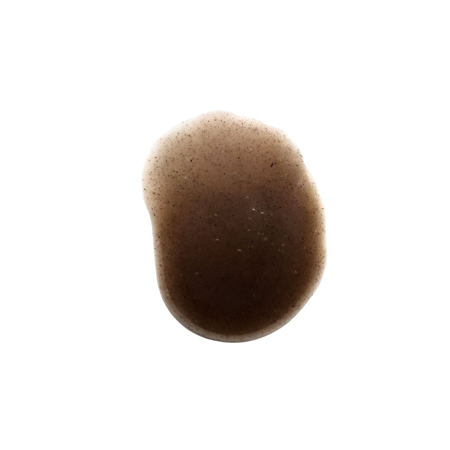 A small, irregularly shaped brown liquid stain appears on a white background. No product or packaging visible. The surface is smooth and matte. There is no typography or graphic design present, and the image shows only the stain on a plain, uncluttered background with no people or additional objects in view. Shot type is close-up from above.